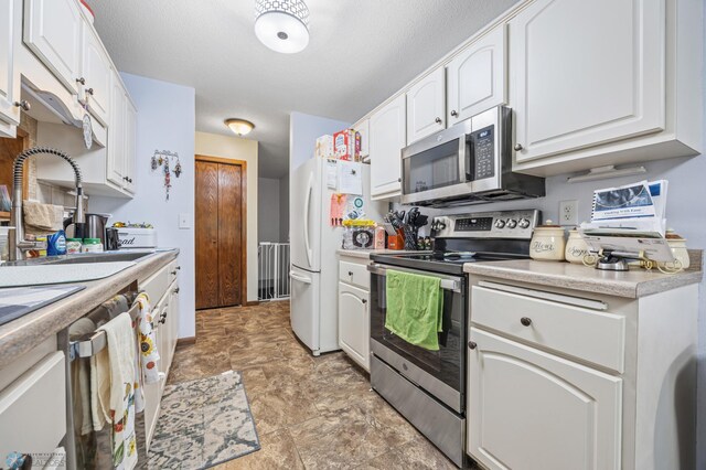 2440 15th St S Unit B14, Fargo, ND 58103 - kitchen featuring stainless steel appliances, white cabinetry, stone finish floors, and light countertops