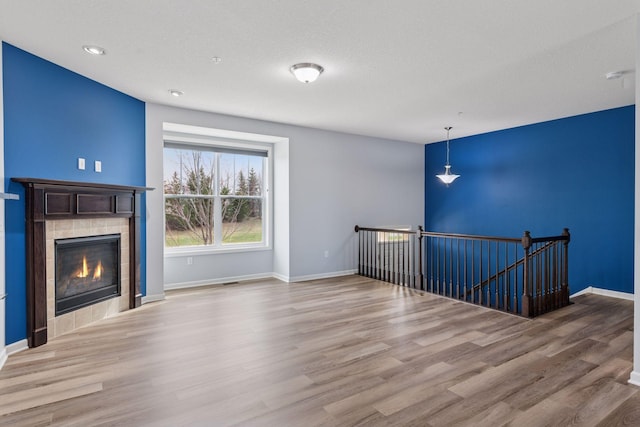 8949 Village Loop, Chanhassen, MN 55317 - unfurnished living room featuring wood finished floors, a tiled fireplace, and recessed lighting