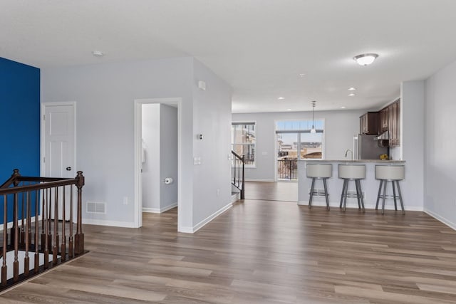 8949 Village Loop, Chanhassen, MN 55317 - kitchen featuring a kitchen breakfast bar, wood finished floors, a peninsula, light countertops, and hanging light fixtures