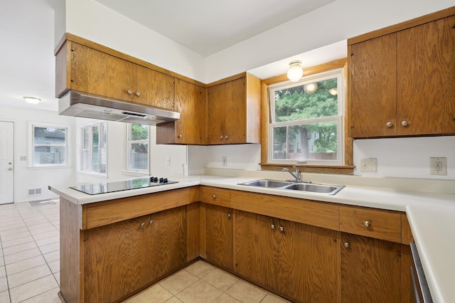 4337 Colorado Ave N, Crystal, MN 55422 - kitchen with black electric stovetop, ventilation hood, brown cabinetry, and light tile patterned flooring
