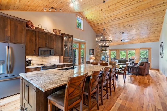 34792 Shore Ln, Crosslake, MN 56442 - kitchen featuring stainless steel appliances, wood ceiling, high vaulted ceiling, light wood-style flooring, and light stone counters