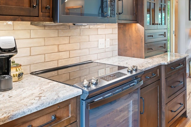 34792 Shore Ln, Crosslake, MN 56442 - kitchen with tasteful backsplash, light stone counters, electric range, and dark brown cabinetry