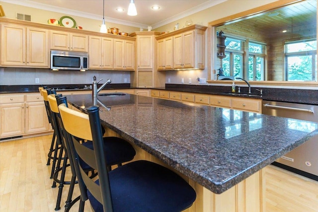 2719 Spring Lake Rd SW, Prior Lake, MN 55372 - kitchen featuring appliances with stainless steel finishes, light brown cabinetry, an island with sink, light wood-type flooring, and ornamental molding