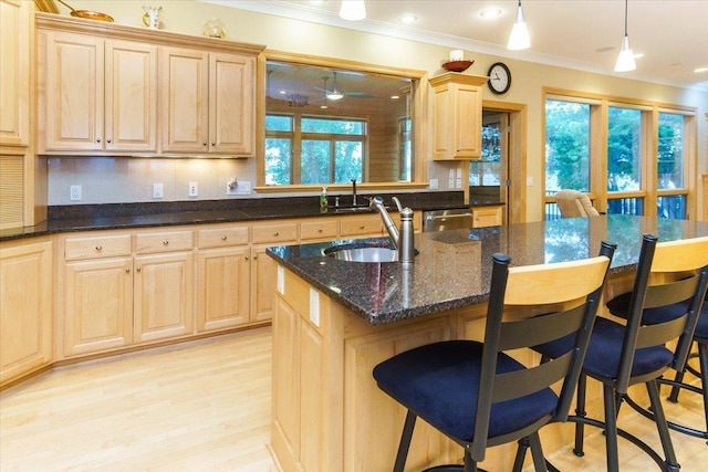 2719 Spring Lake Rd SW, Prior Lake, MN 55372 - kitchen featuring crown molding, light brown cabinets, a breakfast bar, light wood-type flooring, and dark stone countertops