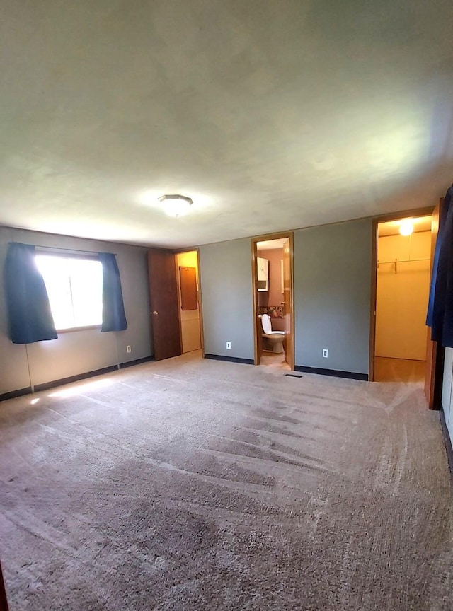1329 US Highway 8, Balsam Lake, WI 54001 - unfurnished bedroom featuring a spacious closet, ensuite bathroom, and light carpet