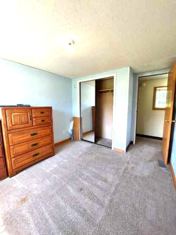 1329 US Highway 8, Balsam Lake, WI 54001 - unfurnished bedroom featuring a closet, a textured ceiling, and light carpet