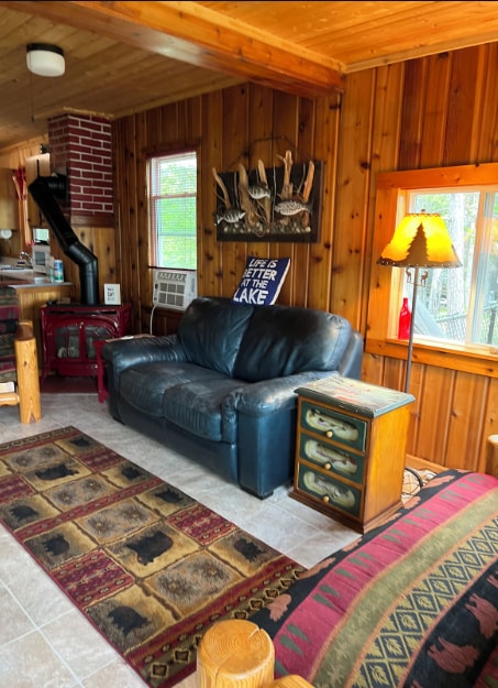 33252 Librarian Ln, Laporte, MN 56461 - living area featuring wooden ceiling, wooden walls, a wood stove, cooling unit, and tile patterned flooring