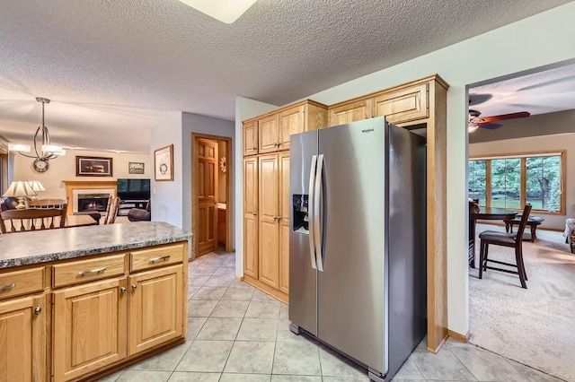 14078 Quince St NW, Andover, MN 55304 - kitchen with stainless steel refrigerator with ice dispenser, a ceiling fan, a textured ceiling, a lit fireplace, and light tile patterned floors