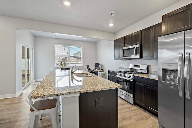 11242 131st Cir N, Dayton, MN 55327 - kitchen with stainless steel appliances, a kitchen breakfast bar, light wood-type flooring, light stone countertops, and a kitchen island with sink