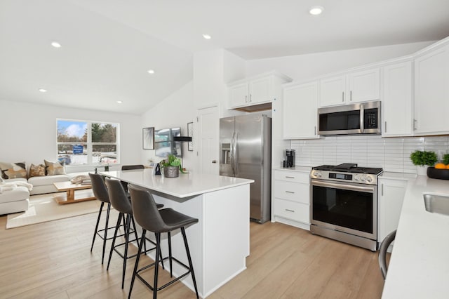 5205 87th St NE, Monticello, MN 55362 - kitchen featuring stainless steel appliances, lofted ceiling, backsplash, white cabinetry, and open floor plan