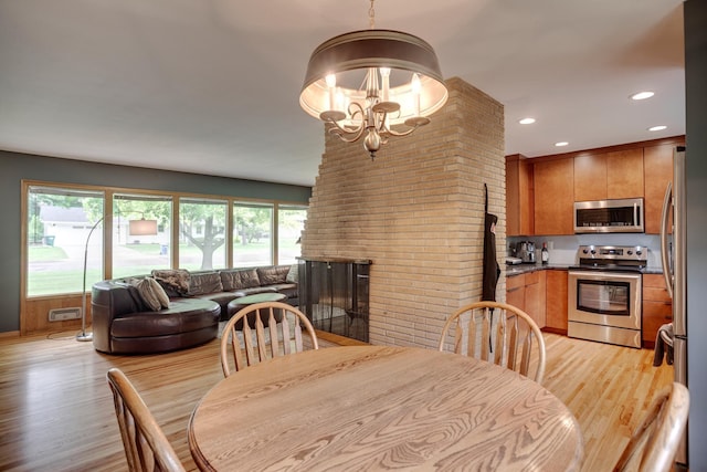 1030 Idaho Ave N, Golden Valley, MN 55427 - dining area with light wood-style floors, a chandelier, recessed lighting, brick wall, and a fireplace