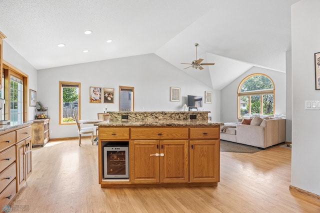 1421 55th Ave S, Fargo, ND 58104 - kitchen featuring wine cooler, light wood-style floors, vaulted ceiling, a ceiling fan, and light stone countertops