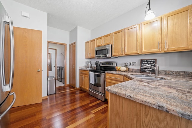 1343 Yorkshire Ln, Shakopee, MN 55379 - kitchen with appliances with stainless steel finishes, dark wood finished floors, light stone counters, washer and clothes dryer, and light brown cabinetry