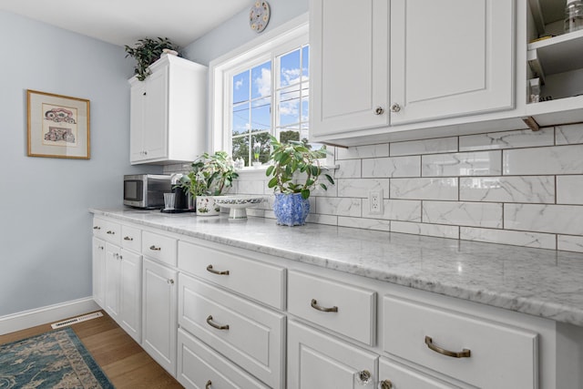 6920 Russell Ave S, Richfield, MN 55423 - kitchen with tasteful backsplash, white cabinetry, dark wood-style floors, and light stone counters