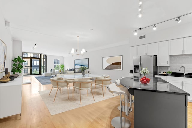 408 1st St Unit 310, Minneapolis, MN 55401 - kitchen featuring stainless steel fridge with ice dispenser, decorative backsplash, a chandelier, white cabinetry, and open floor plan