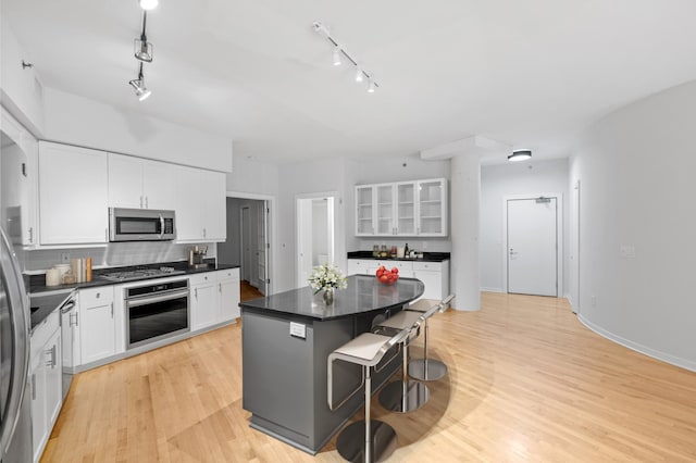 408 1st St Unit 310, Minneapolis, MN 55401 - kitchen featuring stainless steel appliances, rail lighting, a kitchen island, dark countertops, and white cabinets