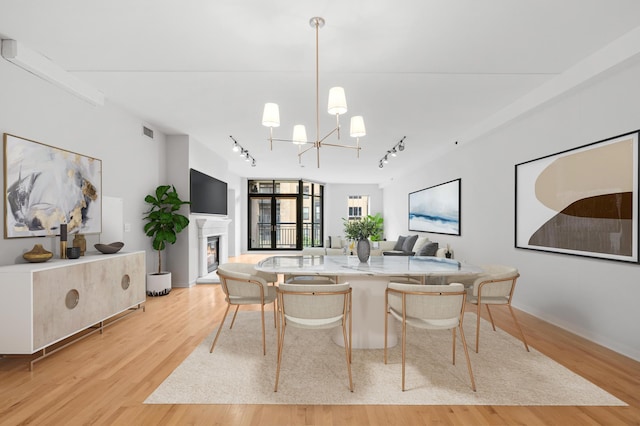 408 1st St Unit 310, Minneapolis, MN 55401 - dining room featuring rail lighting, light wood-style flooring, a lit fireplace, and a chandelier