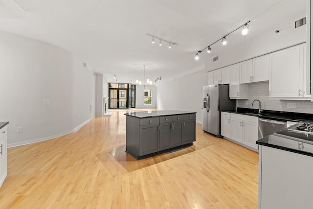 408 1st St Unit 310, Minneapolis, MN 55401 - kitchen with dark countertops, white cabinets, light wood-type flooring, and backsplash