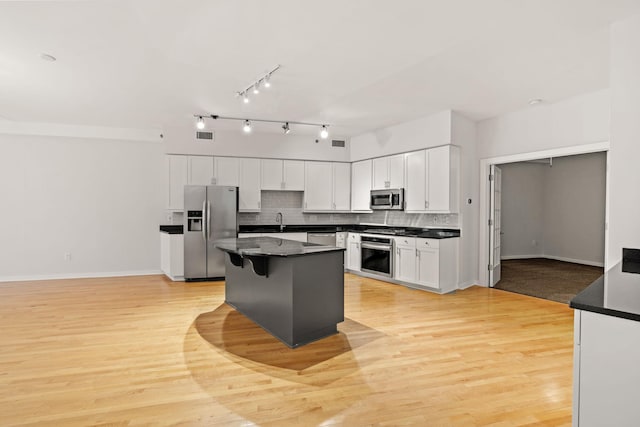 408 1st St Unit 310, Minneapolis, MN 55401 - kitchen with stainless steel appliances, dark countertops, white cabinets, tasteful backsplash, and light wood-type flooring