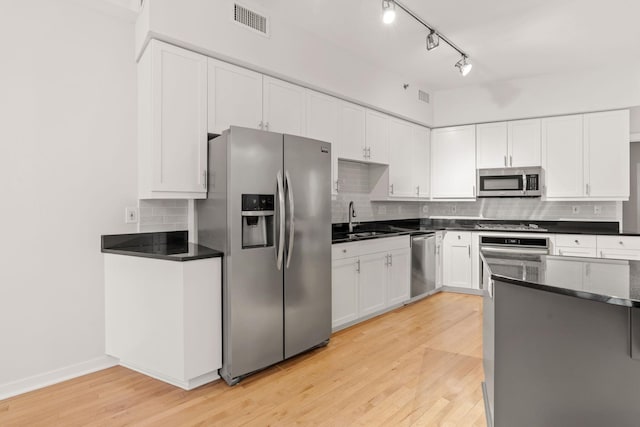 408 1st St Unit 310, Minneapolis, MN 55401 - kitchen featuring stainless steel appliances, white cabinetry, decorative backsplash, and light wood-style floors