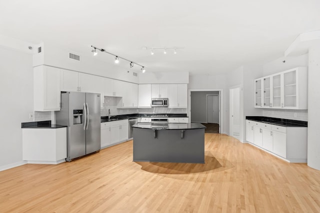 408 1st St Unit 310, Minneapolis, MN 55401 - kitchen featuring appliances with stainless steel finishes, backsplash, dark countertops, light wood finished floors, and white cabinetry