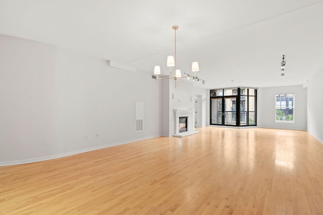 408 1st St Unit 310, Minneapolis, MN 55401 - unfurnished living room featuring a chandelier, light wood-type flooring, rail lighting, and a glass covered fireplace