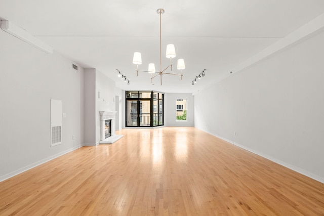 408 1st St Unit 310, Minneapolis, MN 55401 - unfurnished living room with track lighting, a chandelier, light wood finished floors, and a lit fireplace