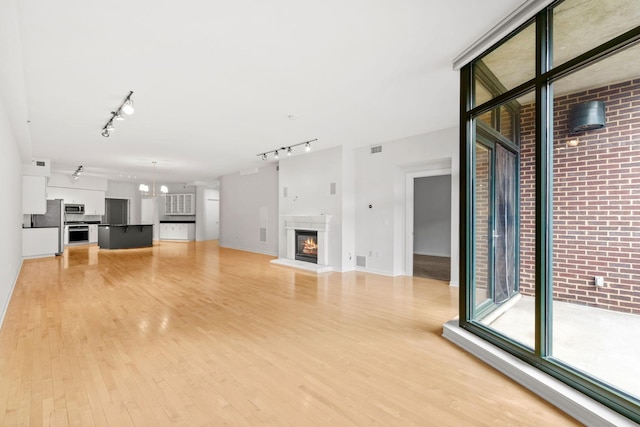 408 1st St Unit 310, Minneapolis, MN 55401 - unfurnished living room with rail lighting, light wood-style floors, and a warm lit fireplace