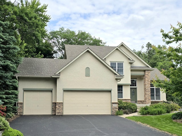 2011 117th Ln NE, Blaine, MN 55449 - view of front of home with stone siding, stucco siding, driveway, a shingled roof, and an attached garage