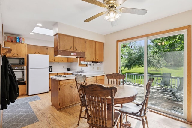 20240 Saint Croix Trl N, Scandia, MN 55073 - kitchen with black appliances, under cabinet range hood, light countertops, a skylight, and light wood finished floors