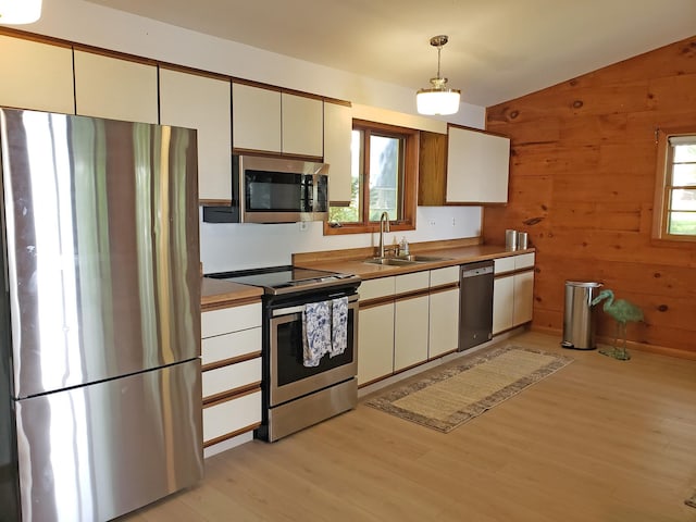 20758 Pike Ave, Aitkin, MN 56431 - kitchen with appliances with stainless steel finishes, light wood-style flooring, vaulted ceiling, wood walls, and pendant lighting