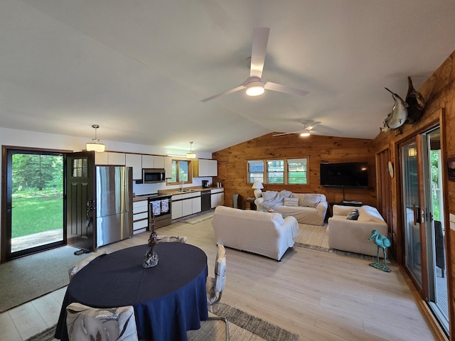 20758 Pike Ave, Aitkin, MN 56431 - living room with wooden walls, light wood-style floors, vaulted ceiling, and a ceiling fan