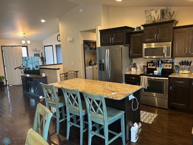 959 29th Ave W, West Fargo, ND 58078 - kitchen with appliances with stainless steel finishes, separate washer and dryer, vaulted ceiling, a kitchen island, and a kitchen breakfast bar