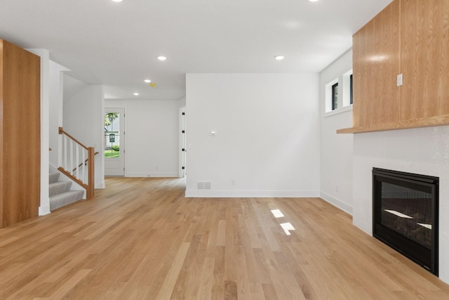2084 Palace Ave, Saint Paul, MN 55105 - unfurnished living room featuring stairs, plenty of natural light, light wood-style floors, recessed lighting, and a tile fireplace