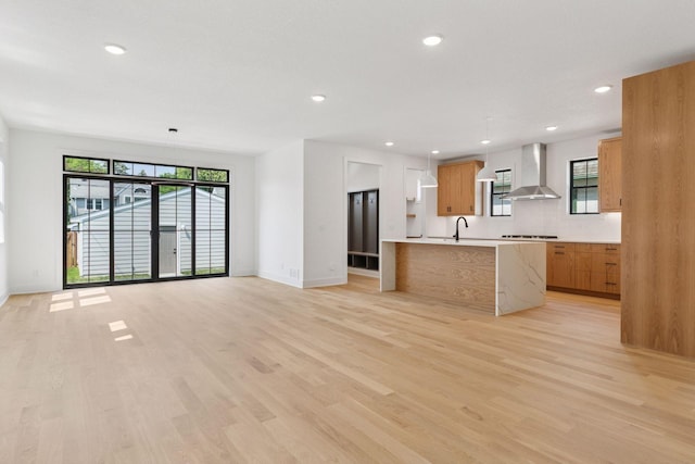 2084 Palace Ave, Saint Paul, MN 55105 - kitchen featuring wall chimney exhaust hood, light countertops, light wood-style flooring, a center island with sink, and recessed lighting