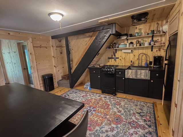 17700 78th St SW, Cokato, MN 55321 - kitchen with black appliances, dark cabinets, dark countertops, light wood finished floors, and wooden walls