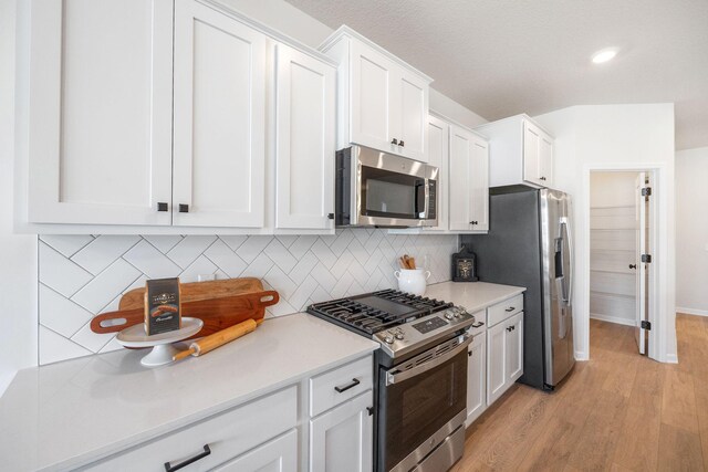 6570 Jody Ave S, Cottage Grove, MN 55016 - kitchen with stainless steel appliances, white cabinetry, light wood-style floors, backsplash, and light countertops