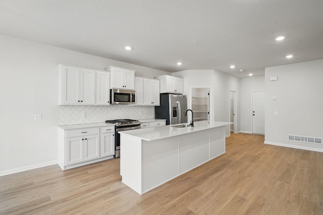 6570 Jody Ave S, Cottage Grove, MN 55016 - kitchen with appliances with stainless steel finishes, backsplash, a center island with sink, recessed lighting, and white cabinetry
