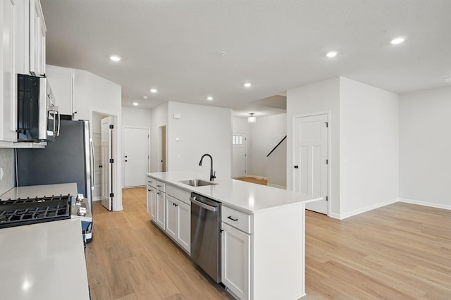 6570 Jody Ave S, Cottage Grove, MN 55016 - kitchen featuring appliances with stainless steel finishes, light wood-style floors, white cabinetry, an island with sink, and recessed lighting