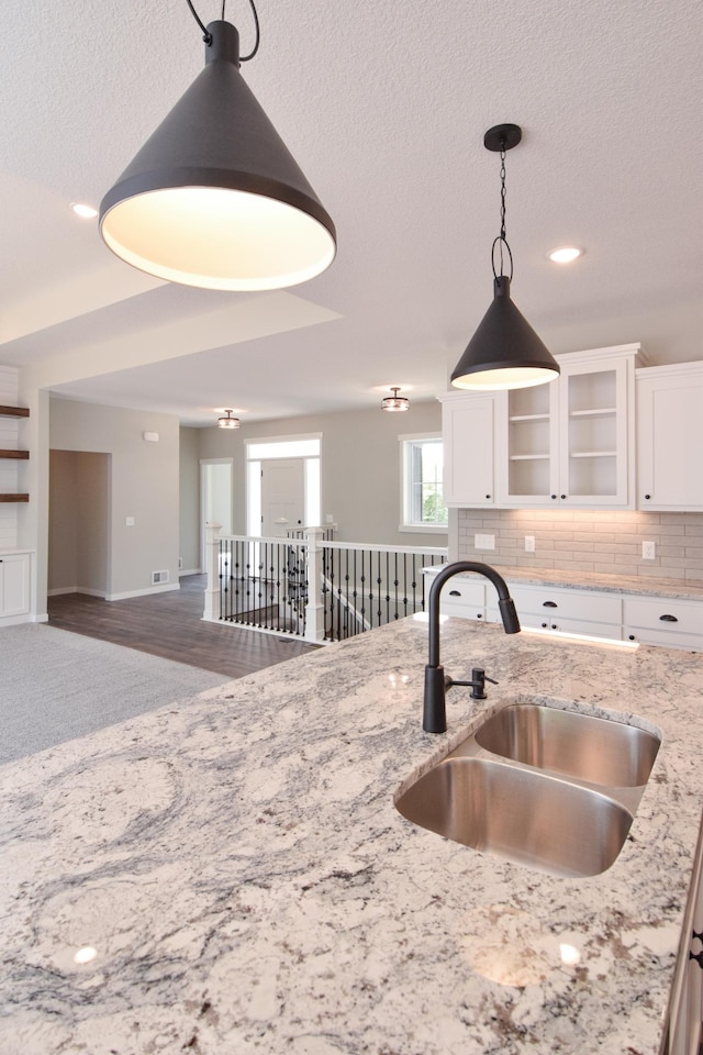 21705 Willys St NE, East Bethel, MN 55011 - kitchen with white cabinets, light stone countertops, glass insert cabinets, hanging light fixtures, and decorative backsplash