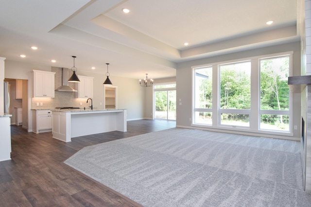 21705 Willys St NE, East Bethel, MN 55011 - unfurnished living room featuring a chandelier, recessed lighting, dark wood-style floors, and a tray ceiling