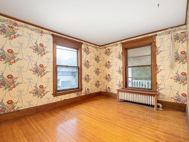 2320 Humboldt Ave S, Minneapolis, MN 55405 - unfurnished room featuring light wood-style floors, radiator heating unit, crown molding, and wallpapered walls