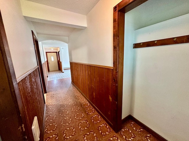 16033 Popplewood Rd NE, Hines Twp, MN 56647 - hallway with a wainscoted wall, wooden walls, arched walkways, tile patterned floors, and a textured ceiling