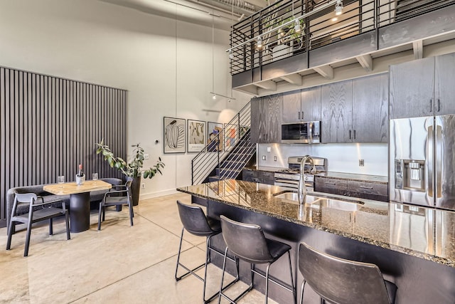 730 Stinson Blvd Unit 504, Minneapolis, MN 55413 - kitchen featuring stainless steel appliances, a high ceiling, concrete floors, dark stone counters, and a breakfast bar area