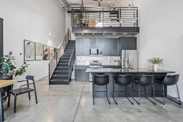 730 Stinson Blvd Unit 504, Minneapolis, MN 55413 - kitchen with stainless steel appliances, a towering ceiling, a kitchen breakfast bar, finished concrete floors, and dark stone countertops