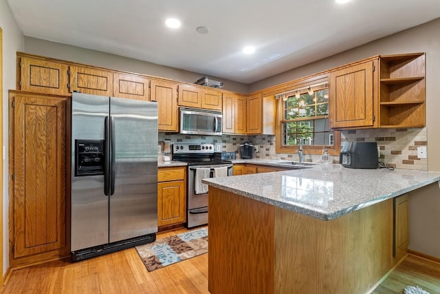 16503 Biscayne Blvd, Eden Prairie, MN 55347 - kitchen with appliances with stainless steel finishes, a peninsula, light wood-style floors, decorative backsplash, and light stone counters