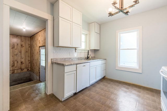 610 2nd St SW, Wadena, MN 56482 - kitchen featuring white dishwasher, light countertops, white cabinets, a chandelier, and wooden walls