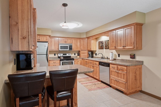 1648 Comstock Ln N, Plymouth, MN 55447 - kitchen with stainless steel appliances, a peninsula, a textured ceiling, pendant lighting, and a kitchen bar