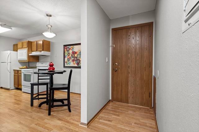4 Pine Tree Dr Unit 218, Arden Hills, MN 55112 - kitchen with white appliances, under cabinet range hood, light wood-type flooring, a textured wall, and pendant lighting