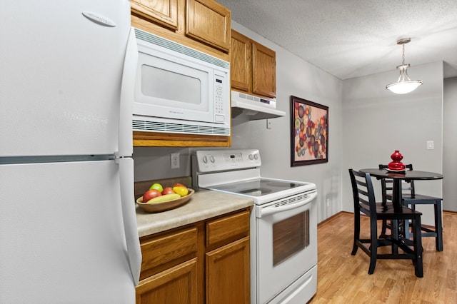 4 Pine Tree Dr Unit 218, Arden Hills, MN 55112 - kitchen featuring white appliances, under cabinet range hood, light wood-style flooring, decorative light fixtures, and brown cabinets